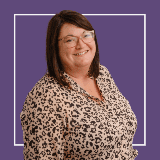 Purple background with white square outline with image of Jacqui Wallis, wearing a cheetah print shirt and glasses, smiling at the camera.