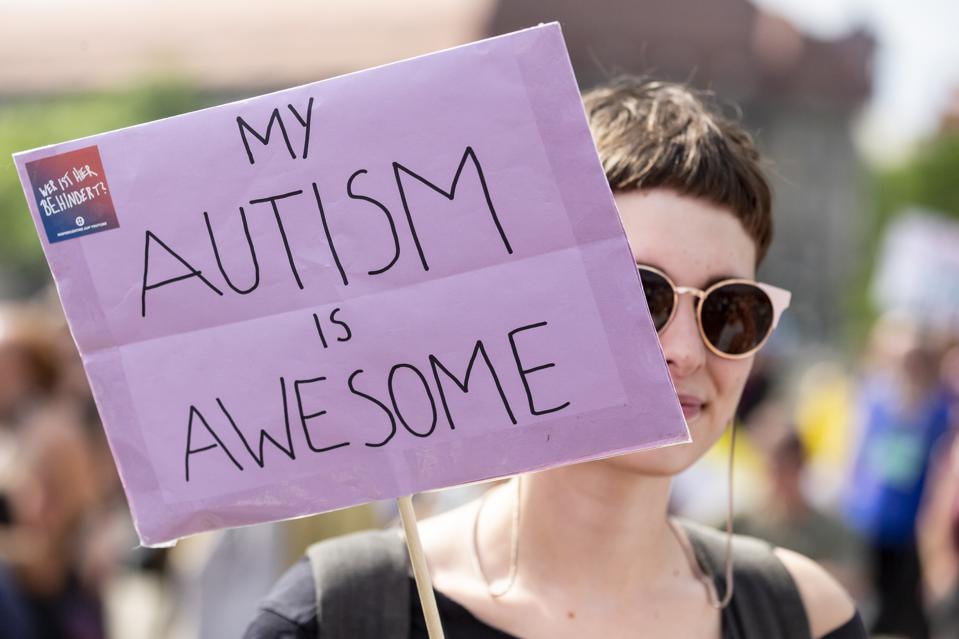 Person holding a protest sign that reads: My Autism is Awesome