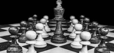 Black and white photo of a chess board with only pawns surrounding a king.