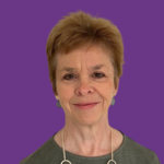Professional headshot of Gill Rudge smiling, with short auburn hair, wearing a green top and silver necklace, against a purple background.