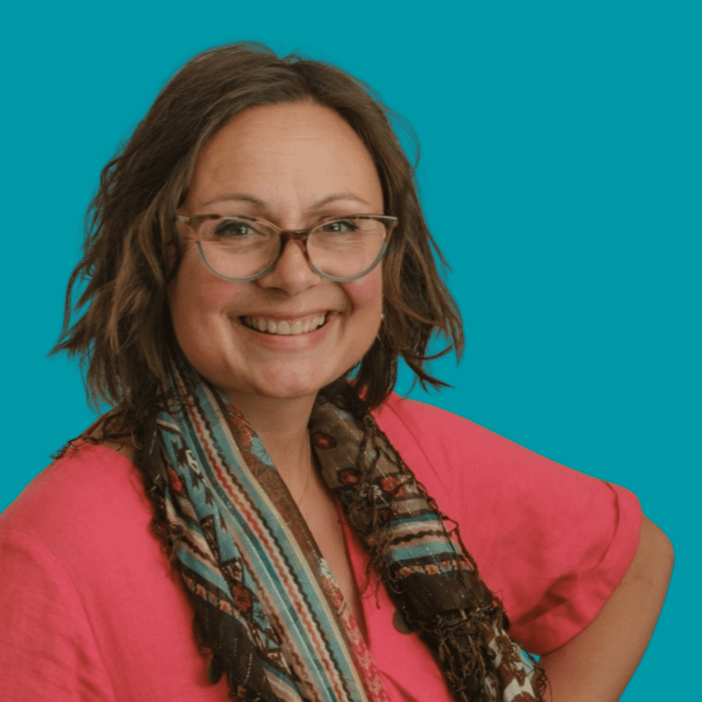 Profile image of Professor Nancy Doyle, smiling at camera wearing a red top with patterned scarf.