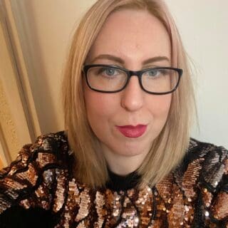 Profile picture of Zoe Farmer looking at camera and wearing a sequin sweater.