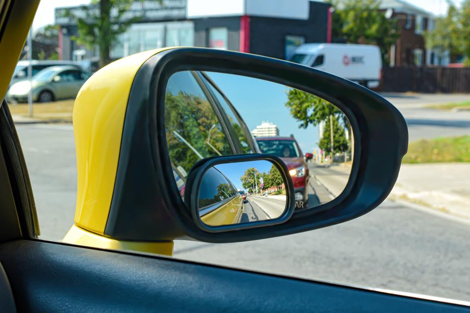 The view from a motor vehicle side mirror through the window, with a blind spot mirror.