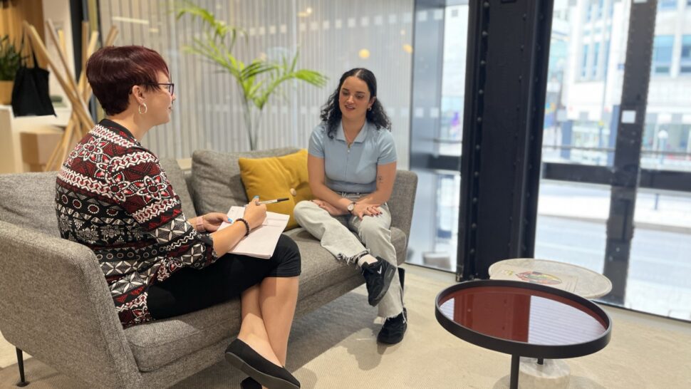 Two people on grey sofa having a discussion