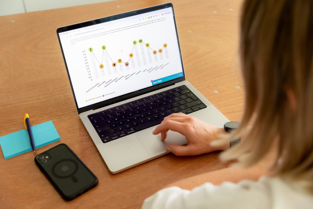 An image of a woman looking at the Genius Finder profile on a laptop screen.