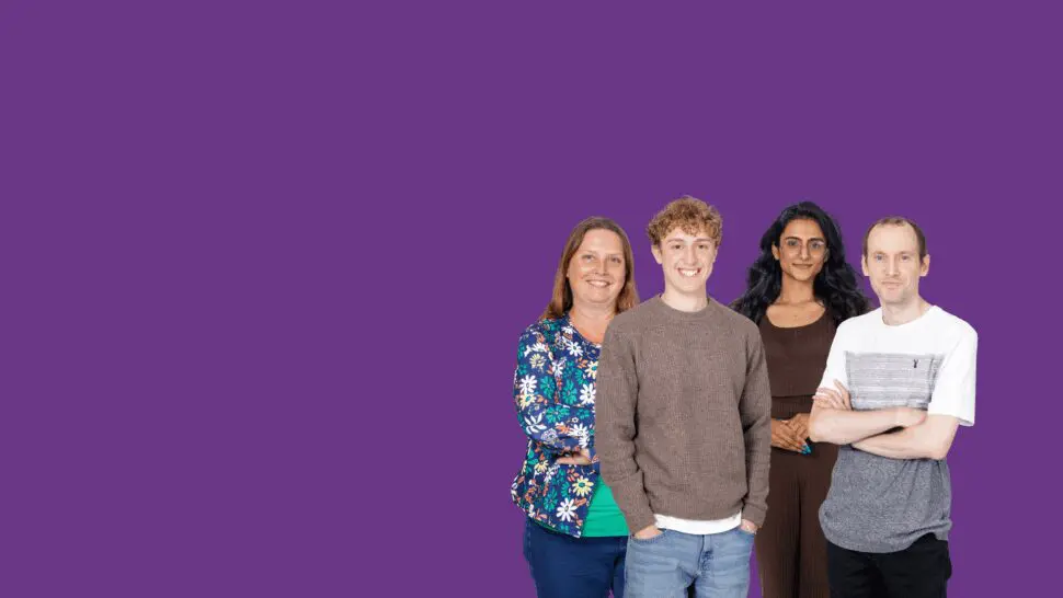 A group of four people standing together against a solid purple background, positioned on the right side of the image. They are dressed in casual clothing, with one person wearing a floral jacket, another in a brown sweater, another in a brown outfit, and another in a white and grey T‑shirt.