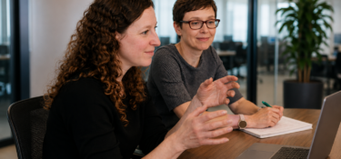 Photo of two individuals sat next to each other at an office desk