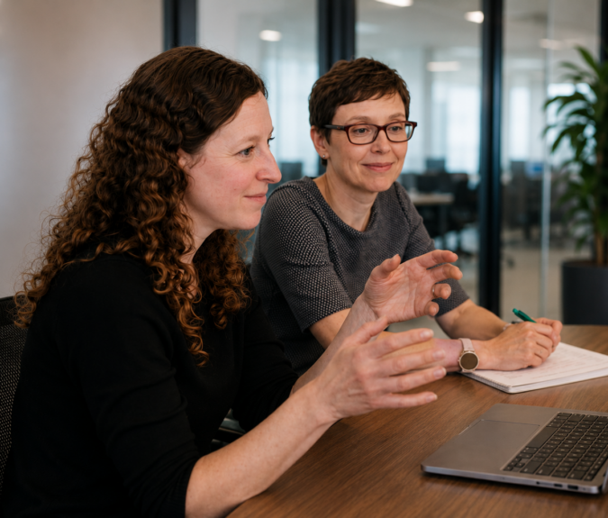 Photo of two individuals sat next to each other at an office desk